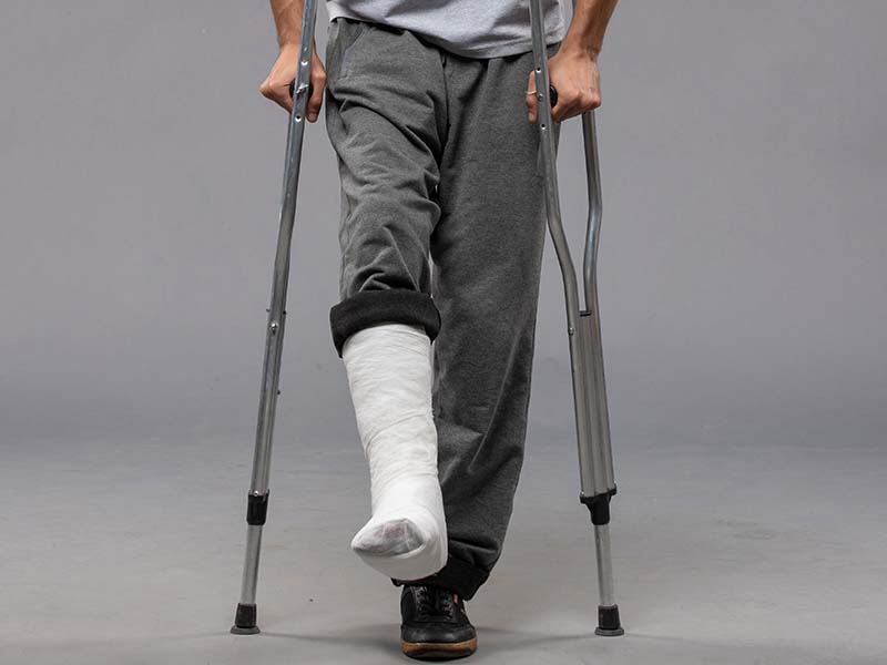 36-KamranAydinov-front-view-young-male-using-crutches-due-broken-foot-grey-wall-pain-disable-leg-broken-accident-foot.jpg